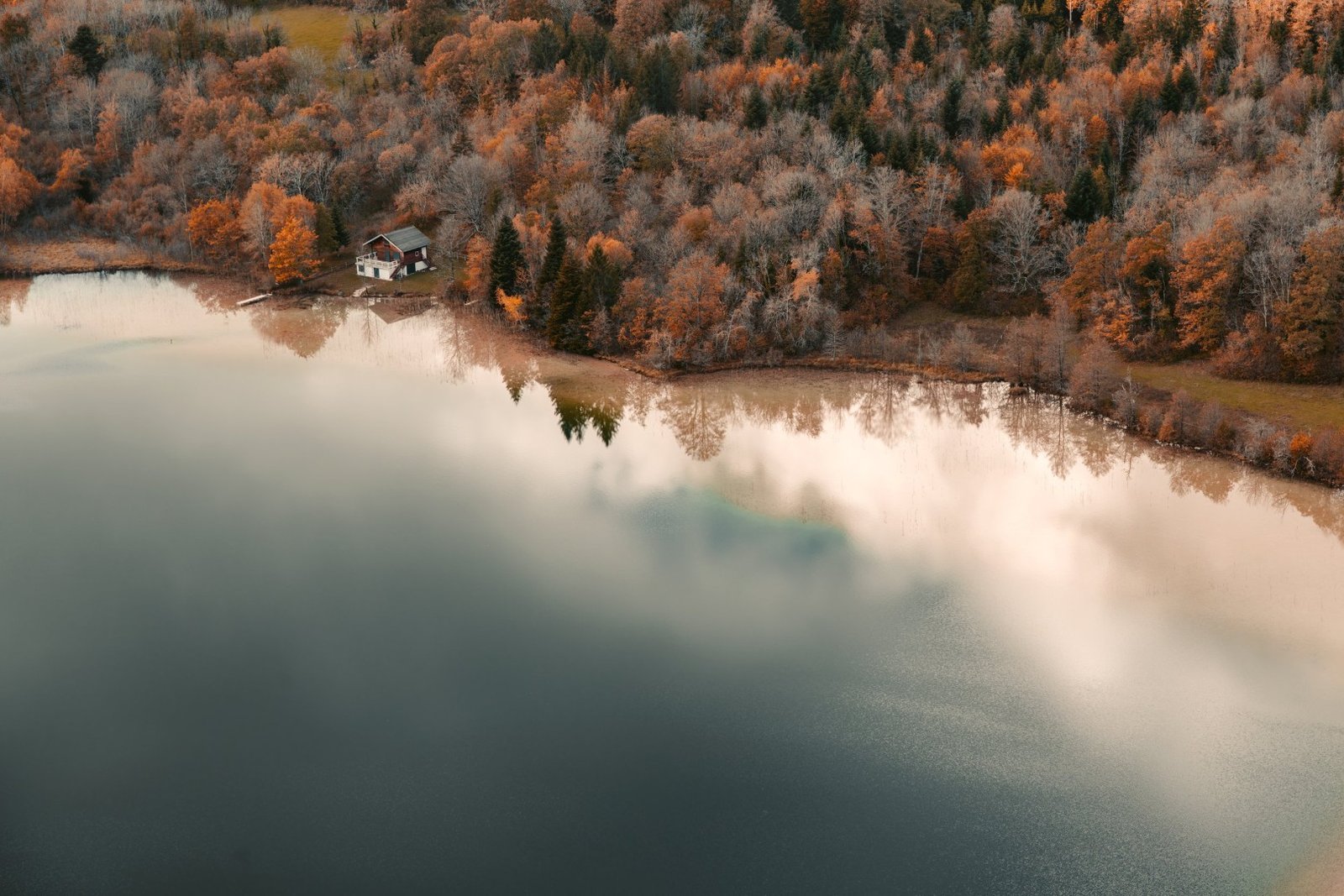 Vue aérienne d'une rive boisée aux couleurs d'automne avec une maison isolée